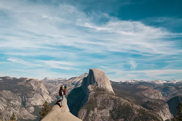 Someone at the summit of a mountain overlooking the surrounding peaks in the area.