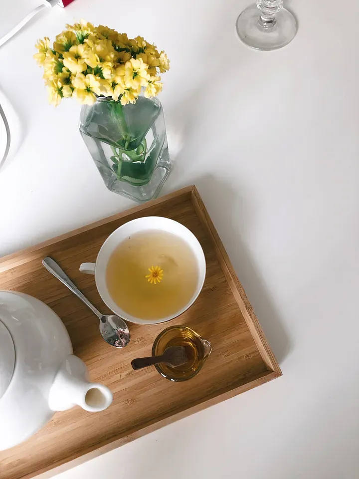 A wooden tray with a teapot and cup of tea.