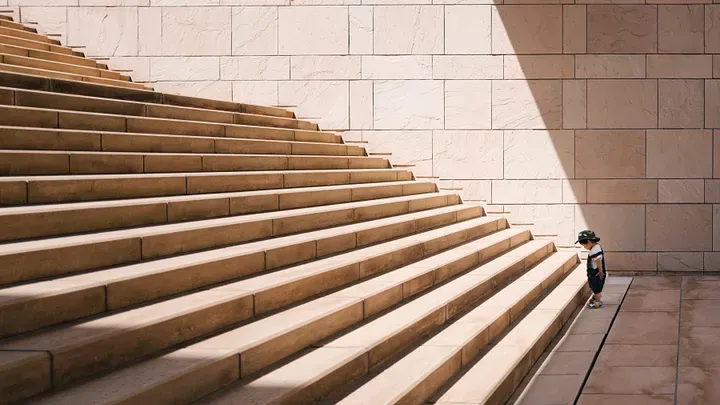 A kid looking down at the beginning of a large flight of outdoor stairs.